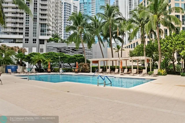 a view of a swimming pool with a lawn chairs and palm trees