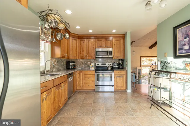 a kitchen with granite countertop a refrigerator a sink a stove top oven a dining table and chairs