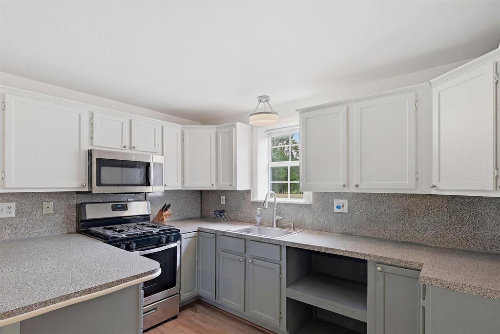2700 Randell Lake Road Denison, TX 75020 - Photo 21 of 39 a kitchen with granite countertop a stove a sink and a microwave