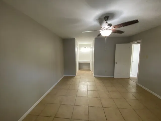 a view of an empty room with a chandelier fan