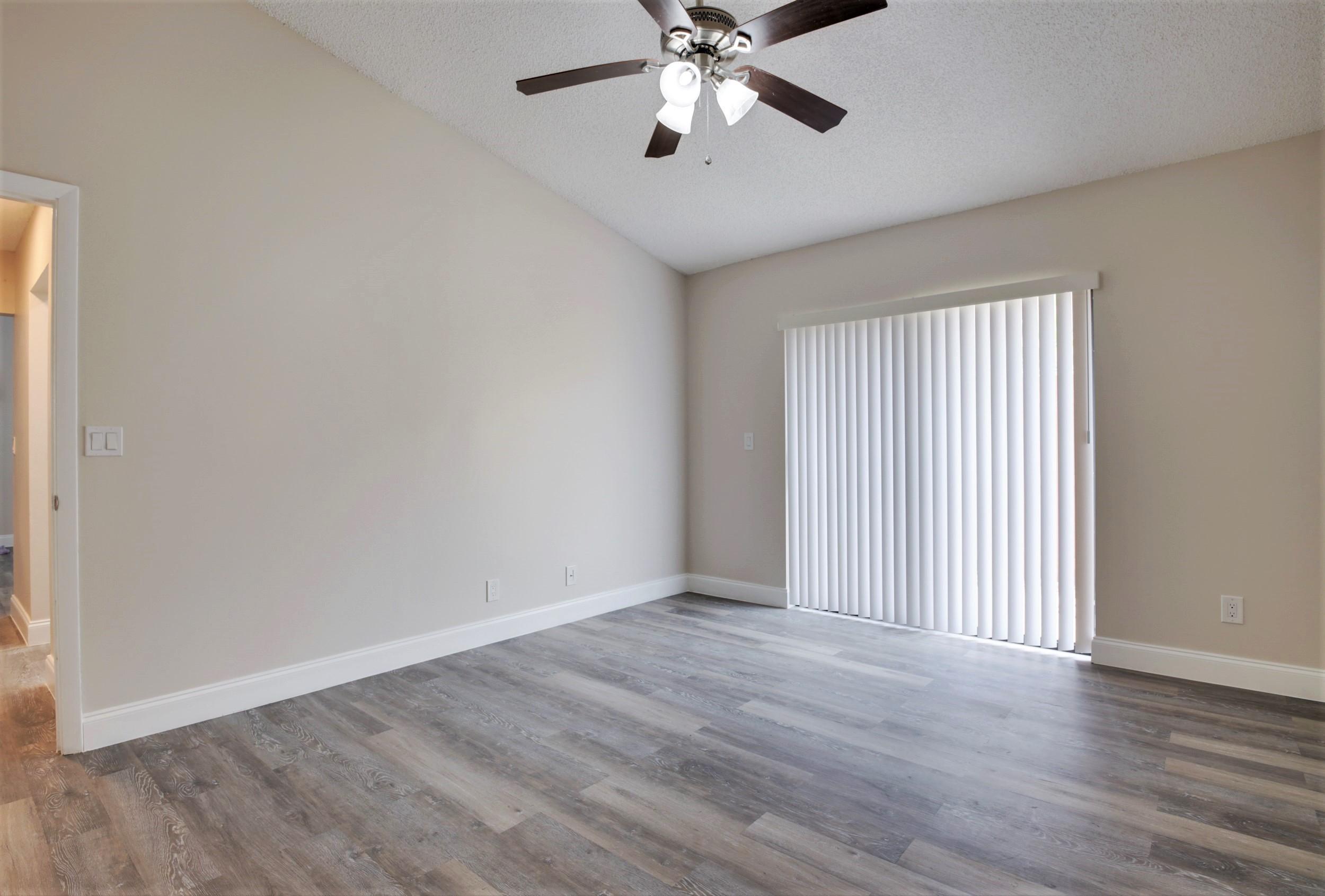 484 Springdale Circle, Unit 48D Palm Springs, FL 33461 - Photo 13 of 59 a view of an empty room with wooden floor and a window