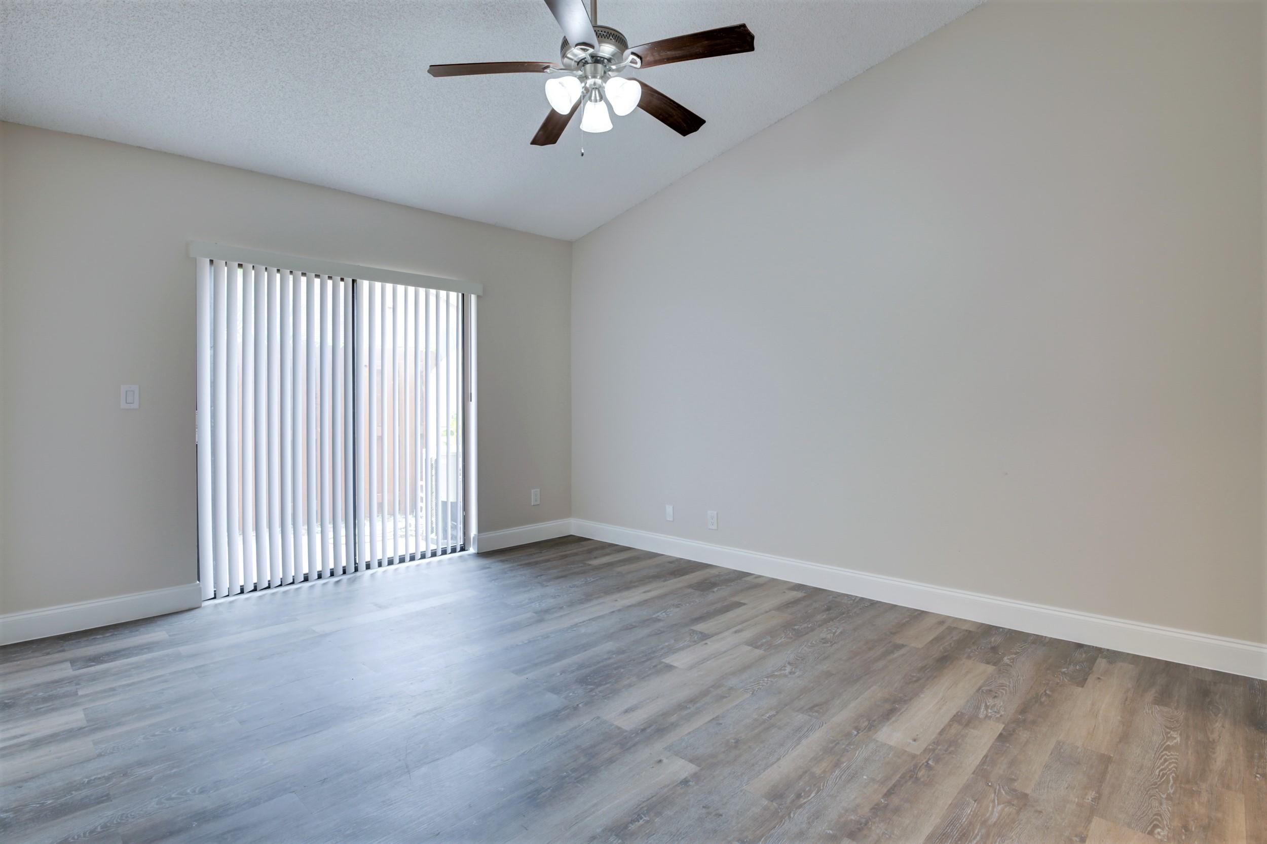484 Springdale Circle, Unit 48D Palm Springs, FL 33461 - Photo 17 of 59 an empty room with wooden floor chandelier fan and windows