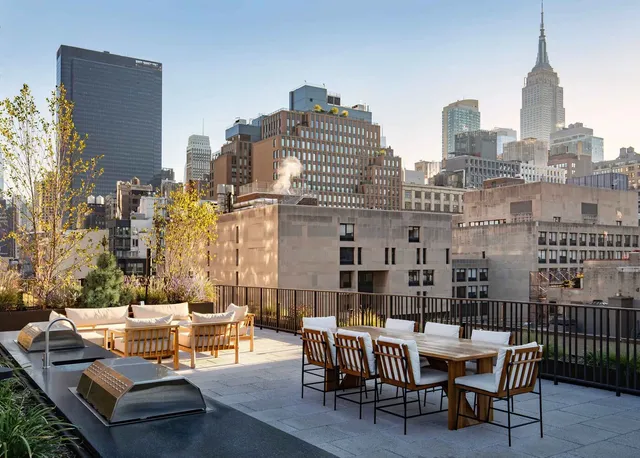 a view of a tall building from a chairs and table in the terrace