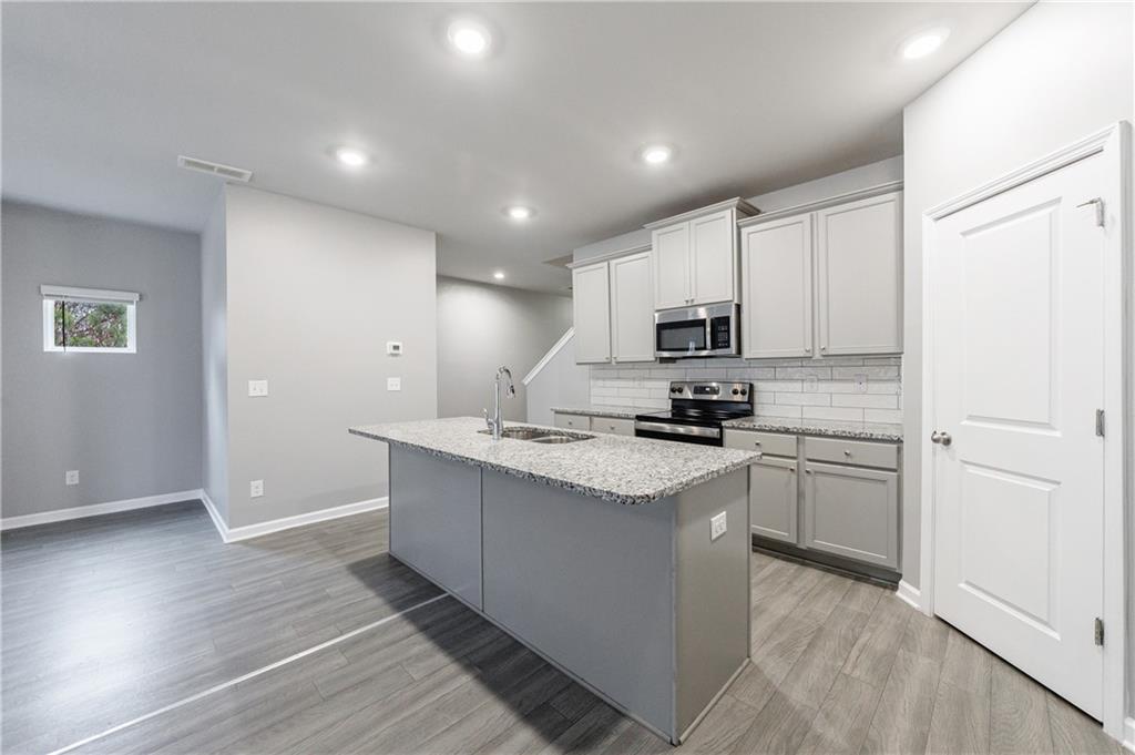 3413 Endurance Court Atlanta, GA 30349 - Photo 14 of 44 a kitchen with kitchen island granite countertop a sink cabinets and stainless steel appliances