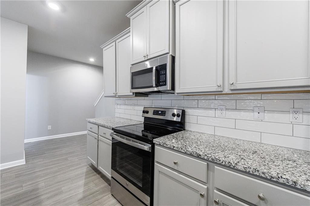 3413 Endurance Court Atlanta, GA 30349 - Photo 15 of 44 a kitchen with granite countertop cabinets stainless steel appliances and wooden floor