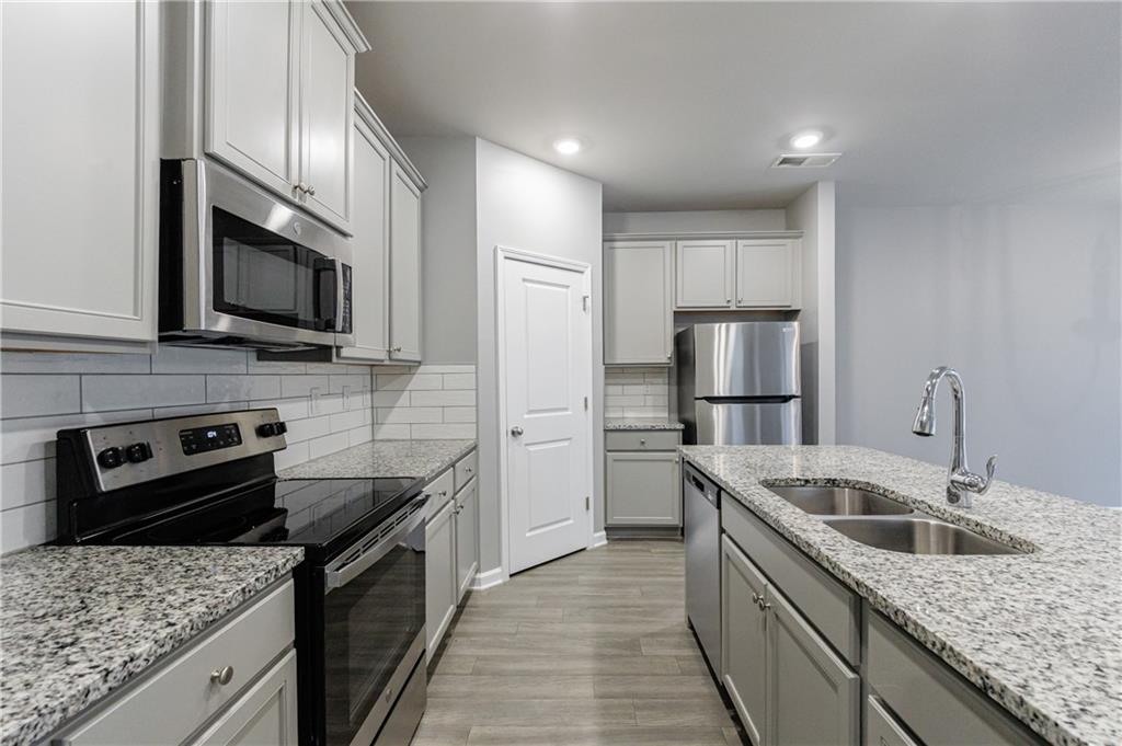 3413 Endurance Court Atlanta, GA 30349 - Photo 17 of 44 a kitchen with stainless steel appliances granite countertop a sink stove microwave and refrigerator