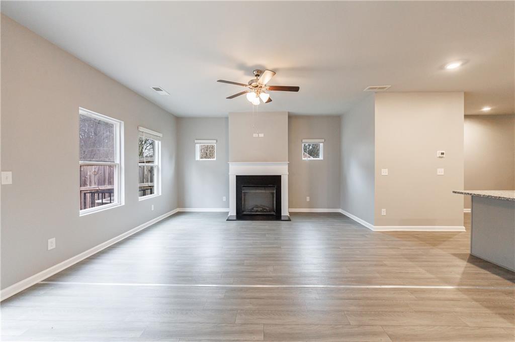 3413 Endurance Court Atlanta, GA 30349 - Photo 21 of 44 an empty room with wooden floor a ceiling fan a fireplace and windows