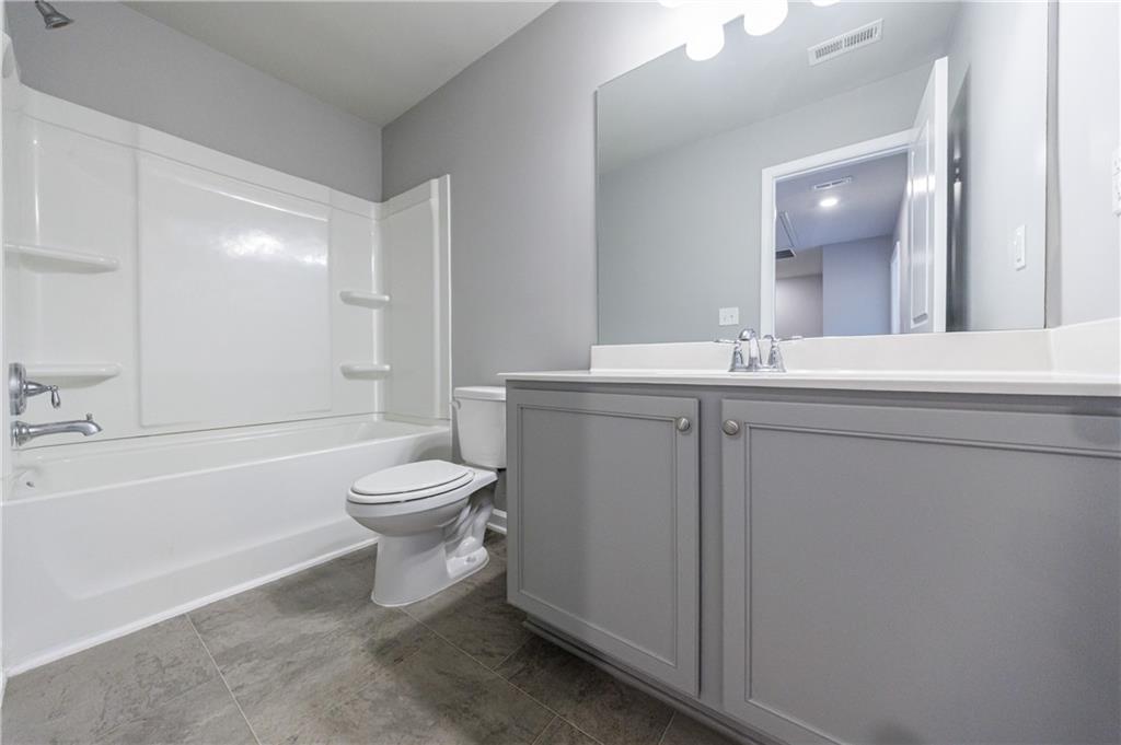 3413 Endurance Court Atlanta, GA 30349 - Photo 44 of 44 a bathroom with a toilet a sink a mirror and a bathtub