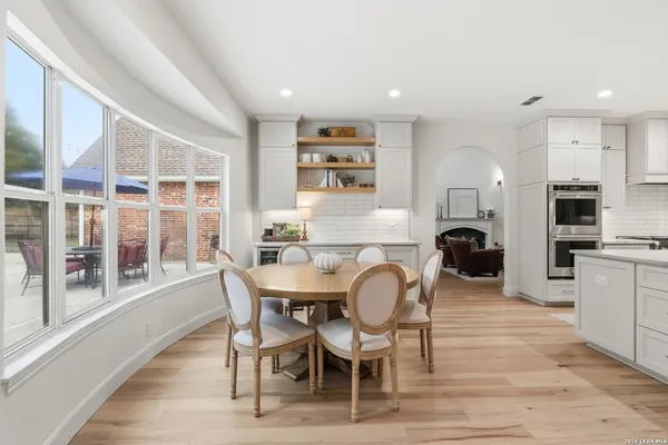 a dining room with stainless steel appliances a dining table and chairs with wooden floor