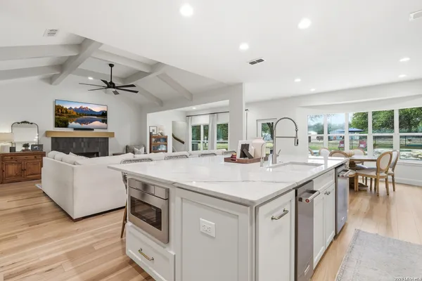 a view of living room with kitchen island stainless steel appliances wooden floor and living room view