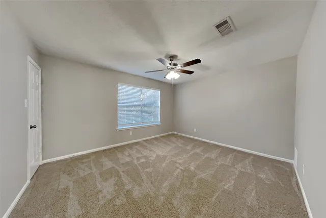a view of an empty room with a chandelier fan