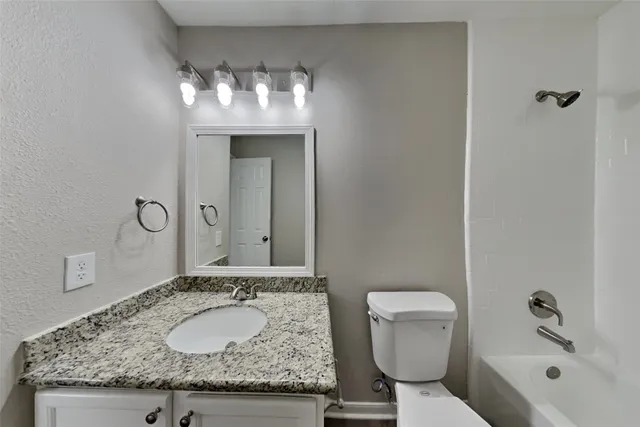 a bathroom with a granite countertop sink a toilet and mirror