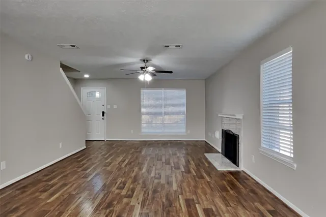 a view of an empty room with a window and wooden floor