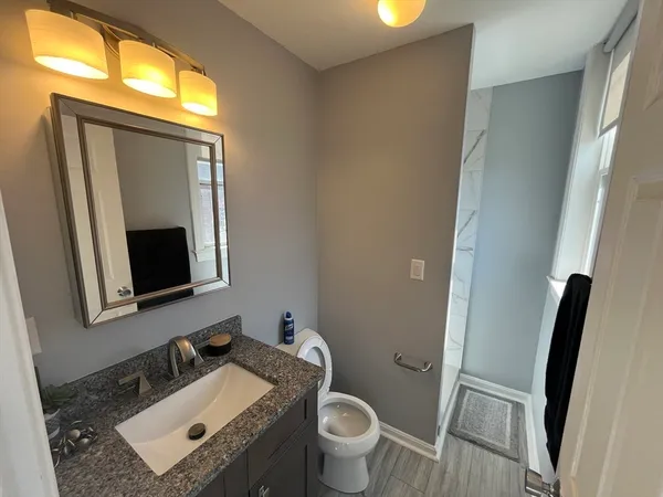 a bathroom with a granite countertop toilet sink and mirror