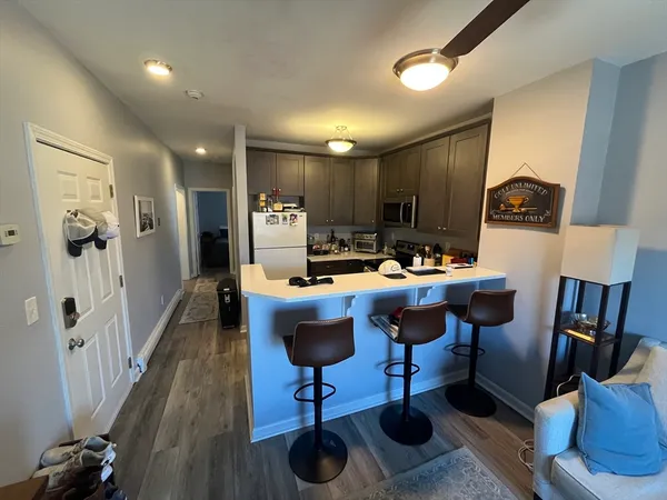 a kitchen with stainless steel appliances kitchen island granite countertop a refrigerator a stove a sink dishwasher and a dining table with wooden floor