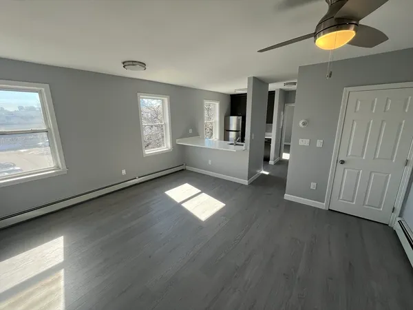 an empty room with wooden floor and windows