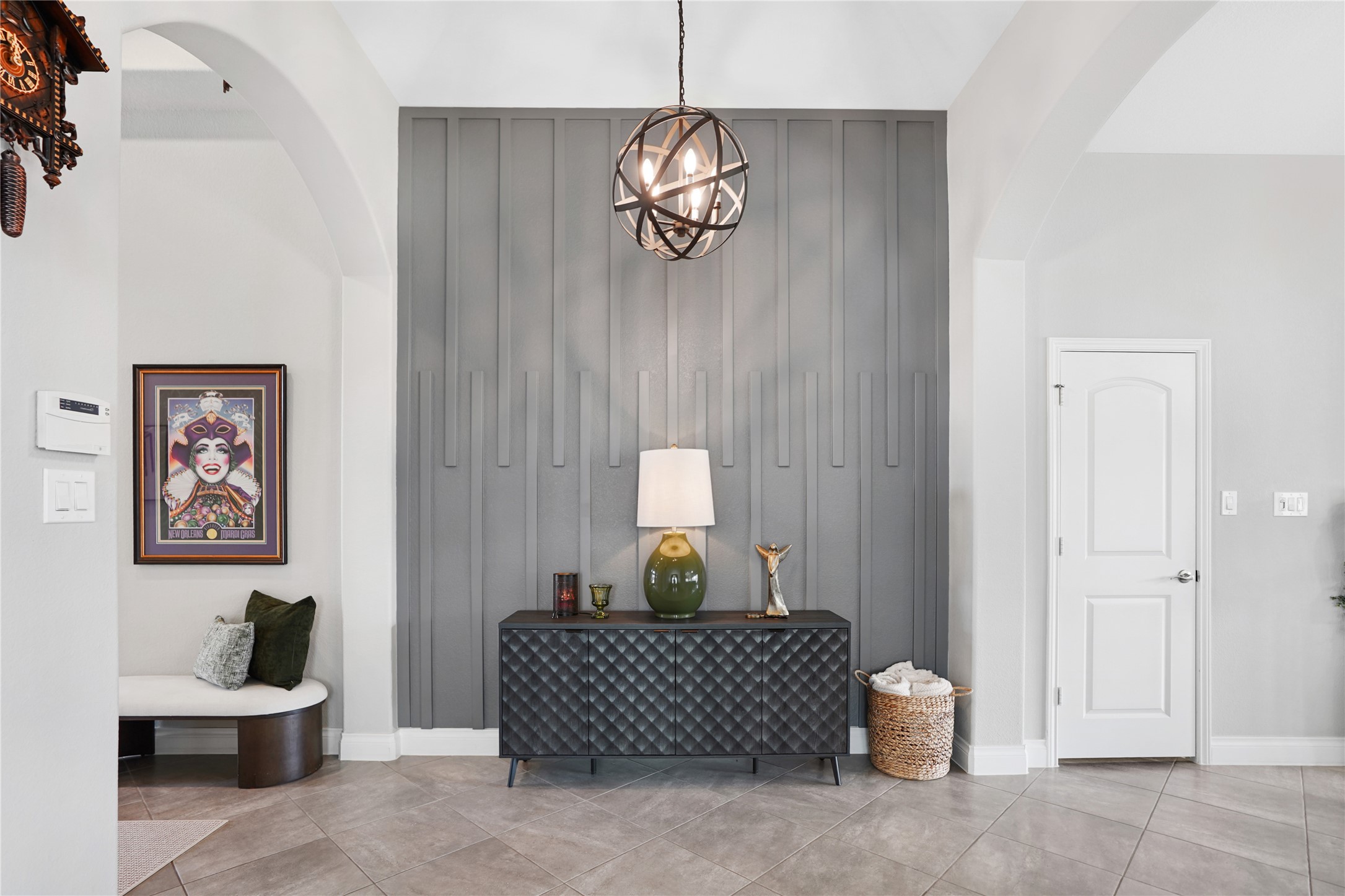 2345 Redwood Ridge Trail Manvel, TX 77578 - Photo 7 of 39 This stylish entryway features a modern accent wall with vertical paneling, a chic geometric light fixture, and a sleek console table. A cozy corner seat adds charm, while neutral tile flooring and soft arches enhance the welcoming atmosphere.