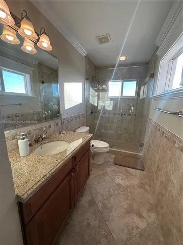 a kitchen with stainless steel appliances kitchen island granite countertop a refrigerator a stove a sink dishwasher a dining table and chairs with wooden floor