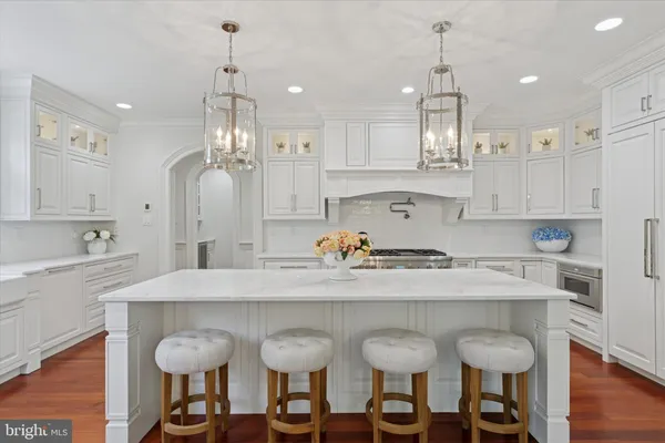 a kitchen with granite countertop a table chairs stove and white cabinets
