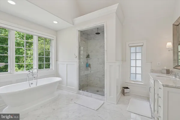 a spacious bathroom with a tub shower and windows