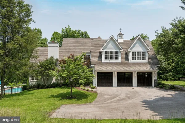 a front view of a house with a garden and trees