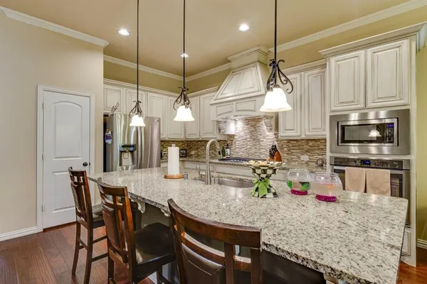 a kitchen with stainless steel appliances granite countertop a stove a refrigerator a oven a sink with a dining table and chairs