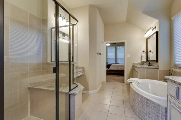 a en suite bathroom with a granite countertop tub shower and mirror