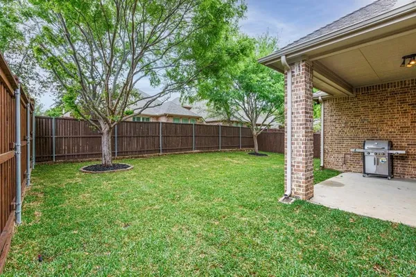 a view of a backyard with a large tree and wooden fence