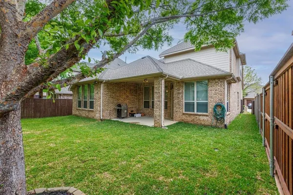 a view of a house with a yard and a large tree