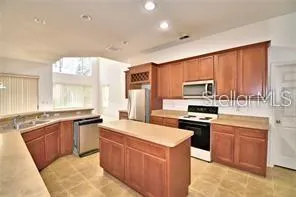 a large kitchen with stainless steel appliances granite countertop a stove top oven a sink dishwasher and a refrigerator
