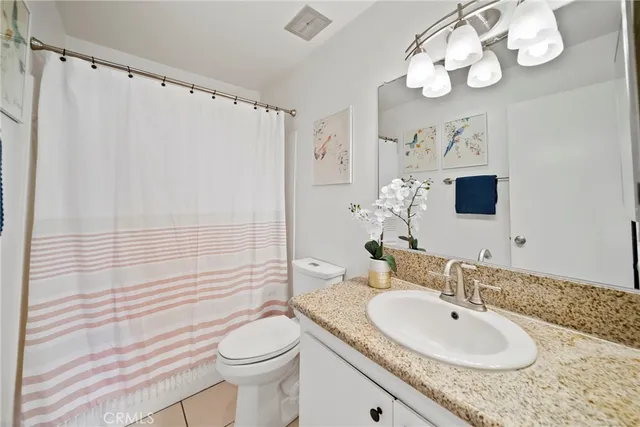 a bathroom with a granite countertop sink a toilet and a mirror
