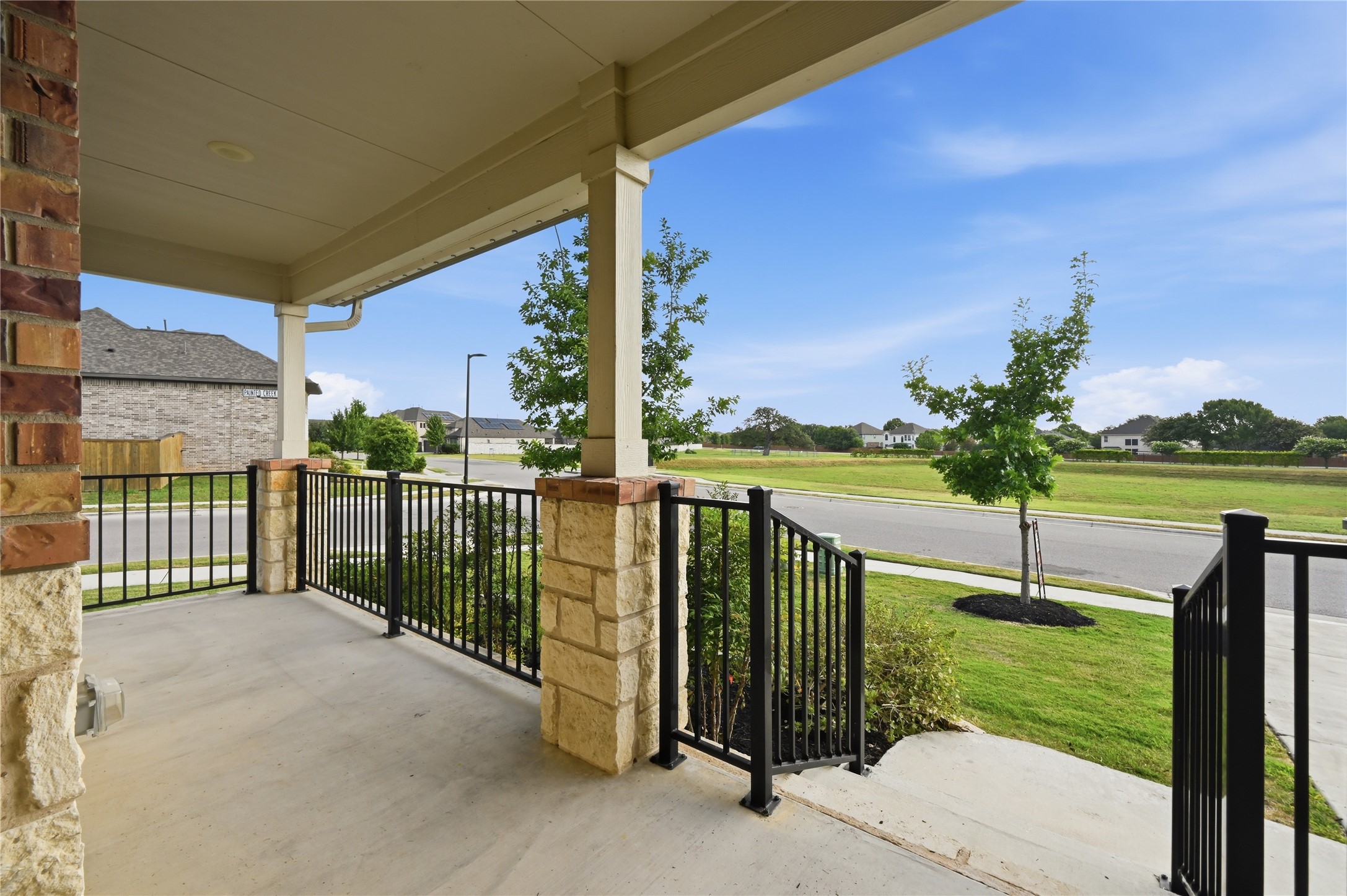426 Cold Riv Run Kyle, TX 78640 - Photo 7 of 34 A welcoming front porch features sturdy stone columns and sleek iron railings, overlooking a quiet street.