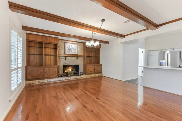 a view of an empty room with wooden floor fireplace and a window