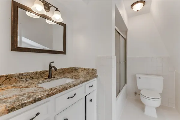 a bathroom with a granite countertop toilet sink and mirror
