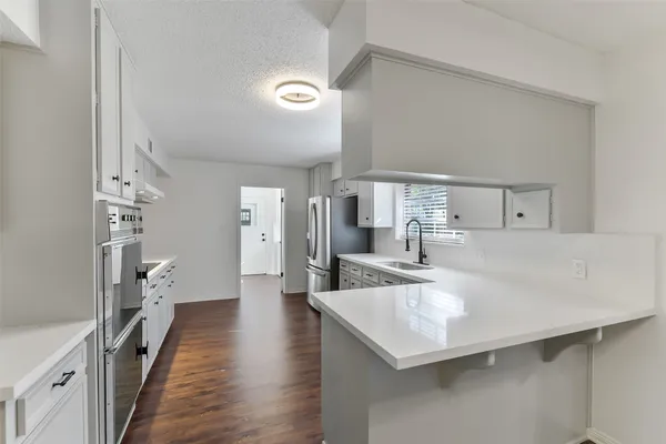 a living room with stainless steel appliances furniture and a kitchen view