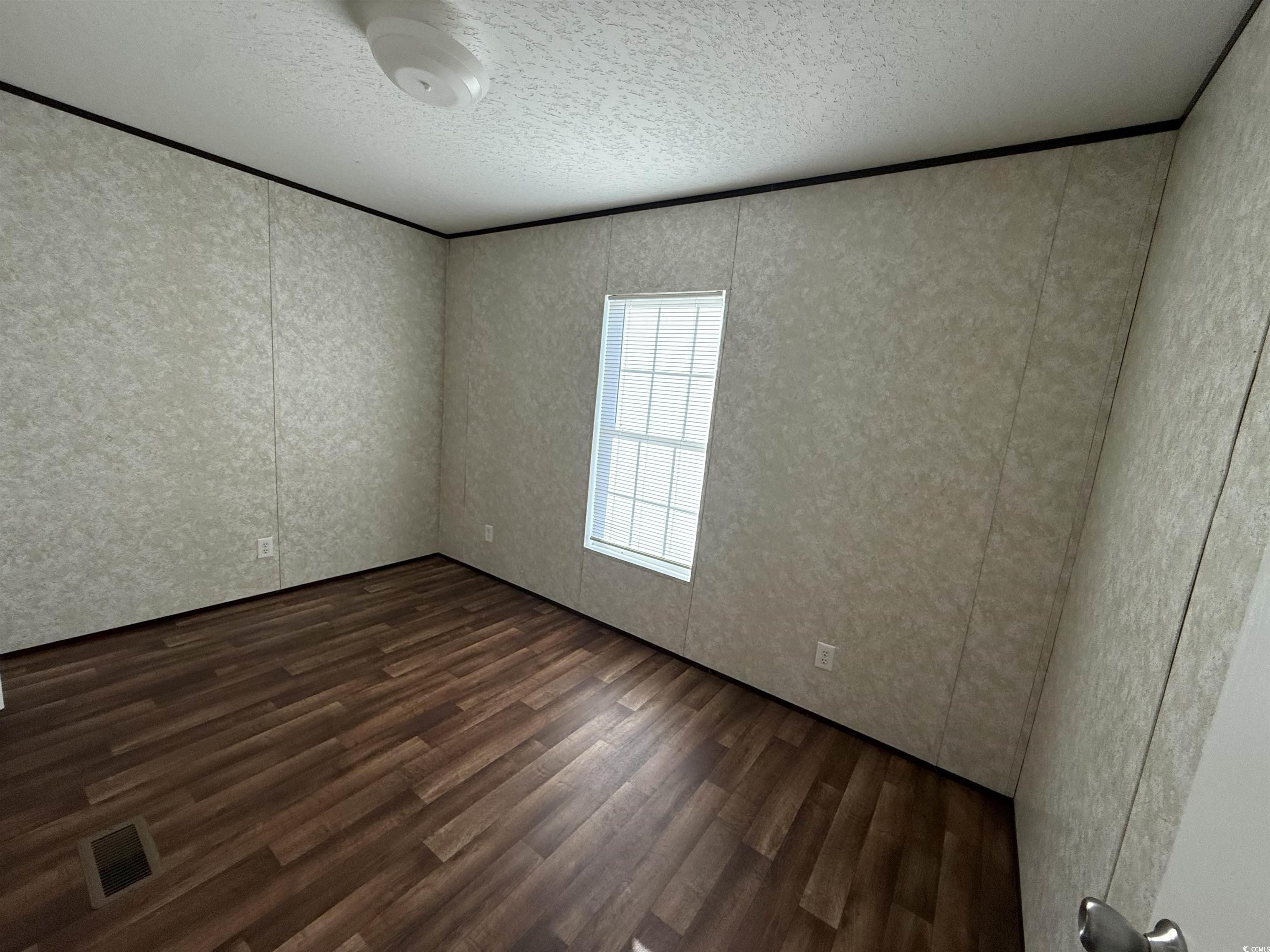 131 Shetland Woods Drive Myrtle Beach, SC 29577 - Photo 10 of 20 Empty room featuring dark wood-type flooring and a textured ceiling
