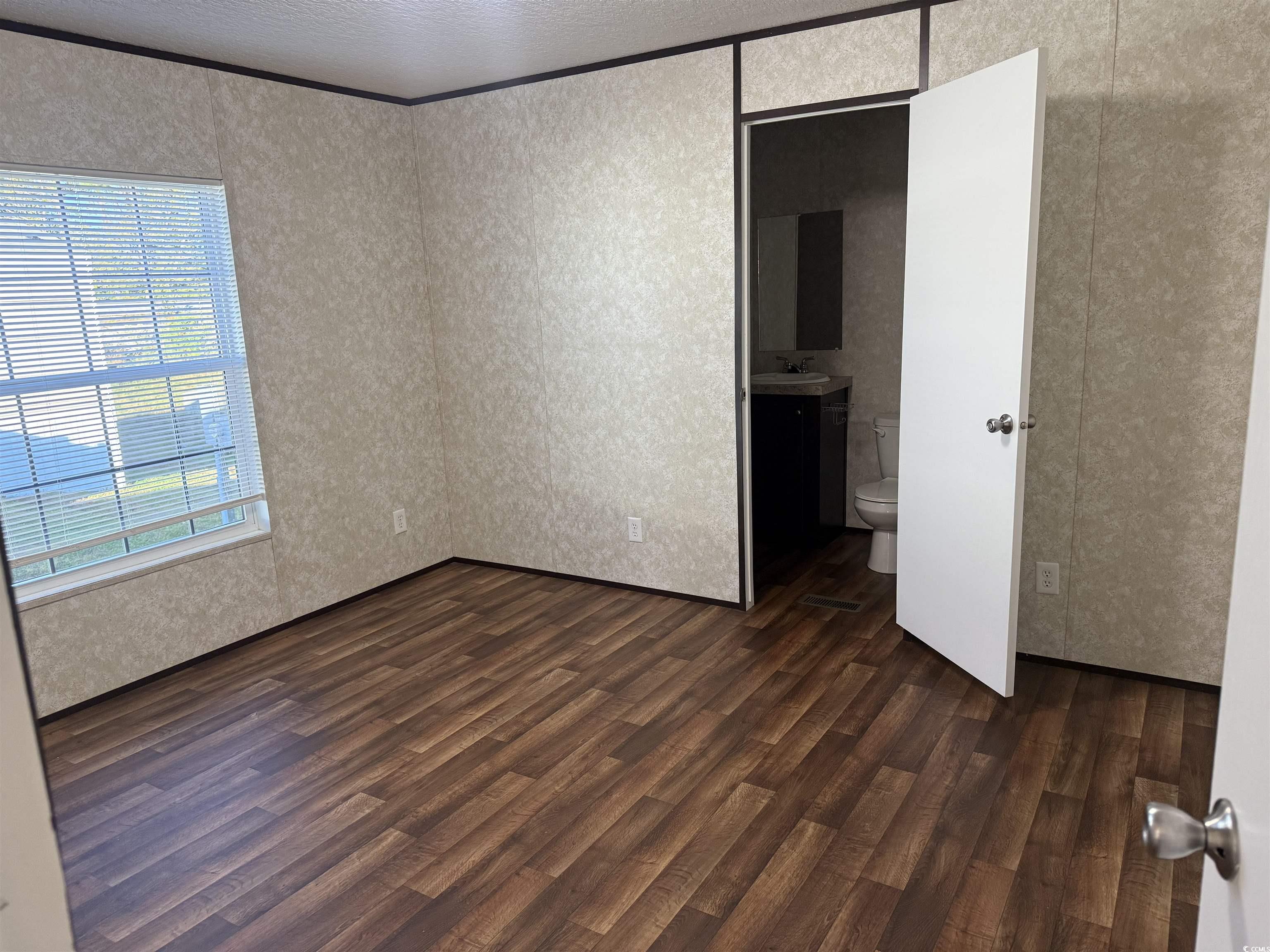 131 Shetland Woods Drive Myrtle Beach, SC 29577 - Photo 11 of 20 Unfurnished bedroom featuring dark wood-style floors, a textured ceiling, and connected bathroom