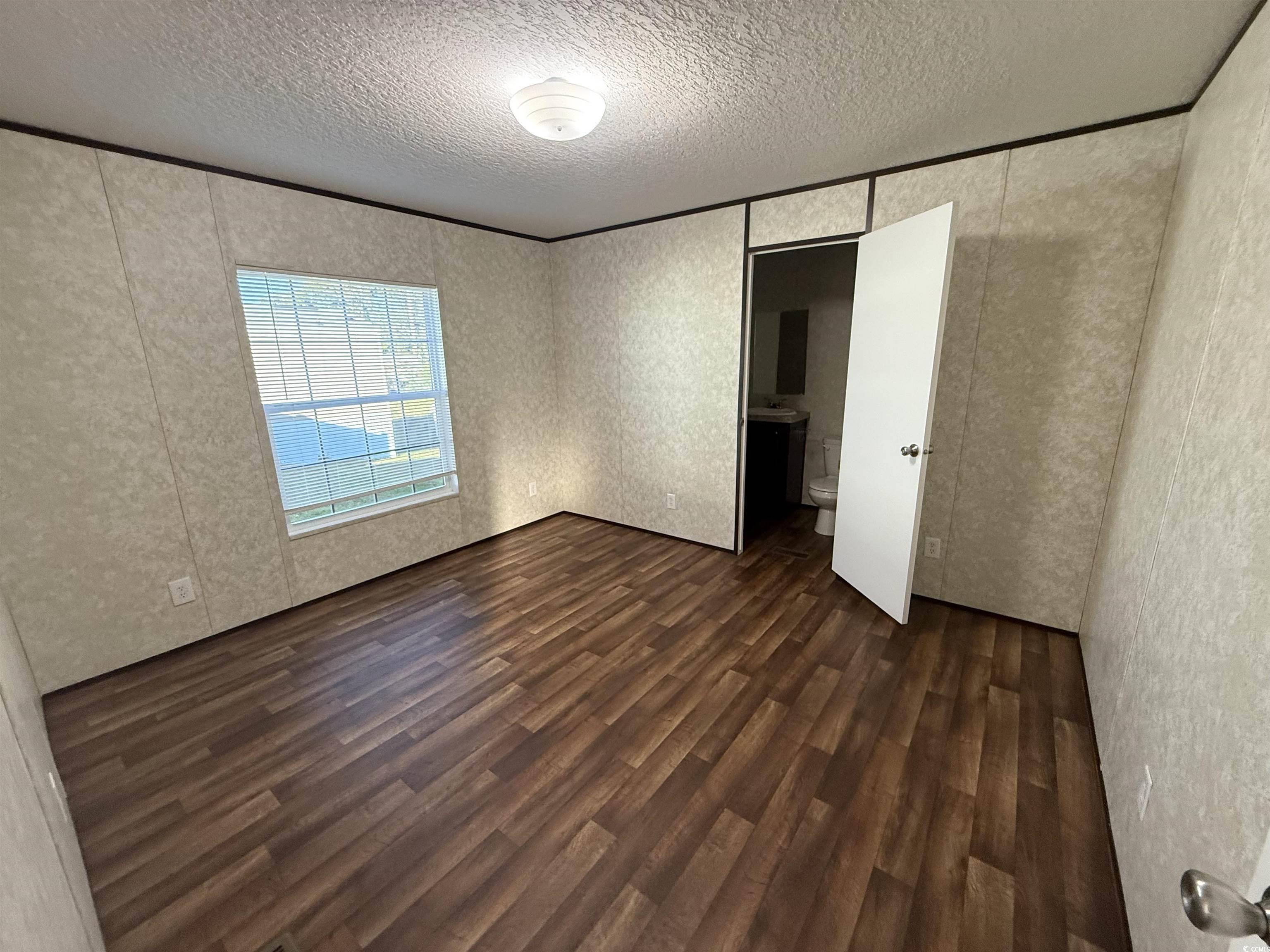 131 Shetland Woods Drive Myrtle Beach, SC 29577 - Photo 12 of 20 Unfurnished bedroom featuring dark wood-style floors, a textured ceiling, and ensuite bath