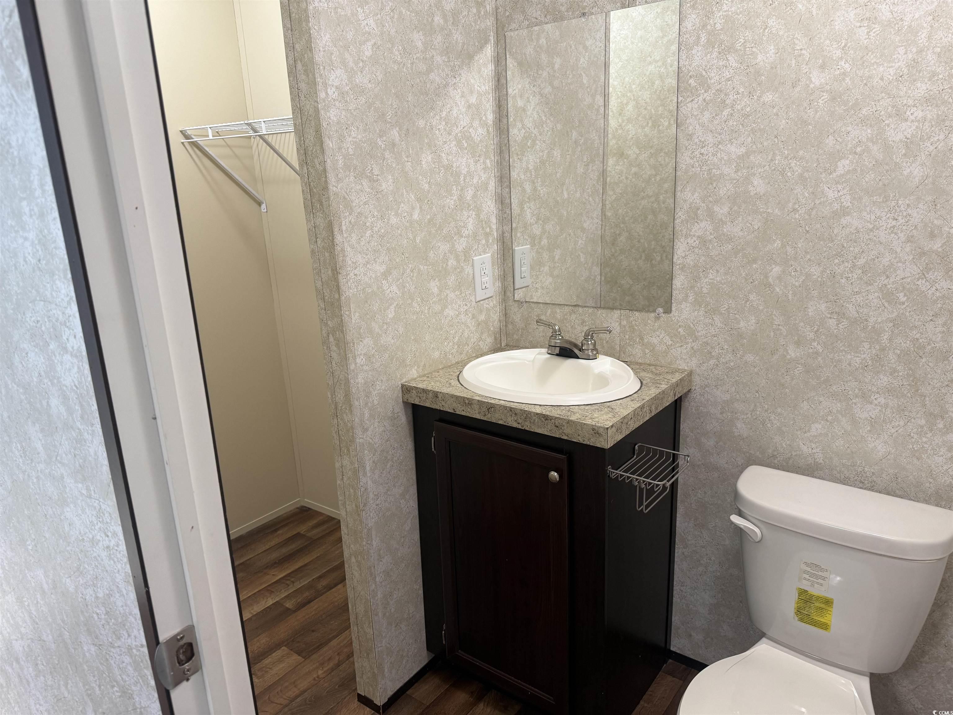 131 Shetland Woods Drive Myrtle Beach, SC 29577 - Photo 13 of 20 Half bathroom with vanity, dark wood-style flooring, and a walk in closet
