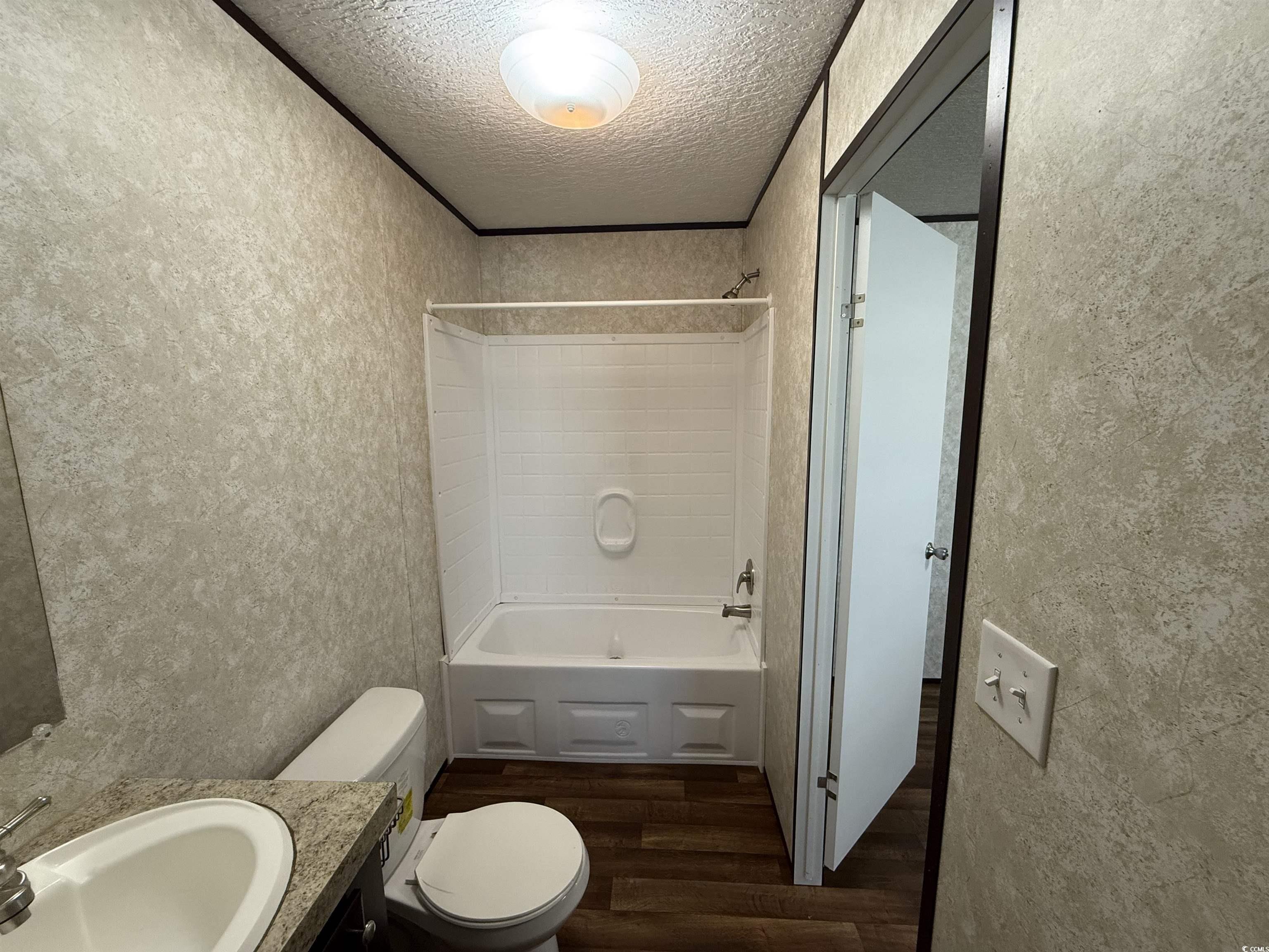 131 Shetland Woods Drive Myrtle Beach, SC 29577 - Photo 14 of 20 Full bath with dark wood-type flooring, vanity, a textured wall, a textured ceiling, and tub / shower combination
