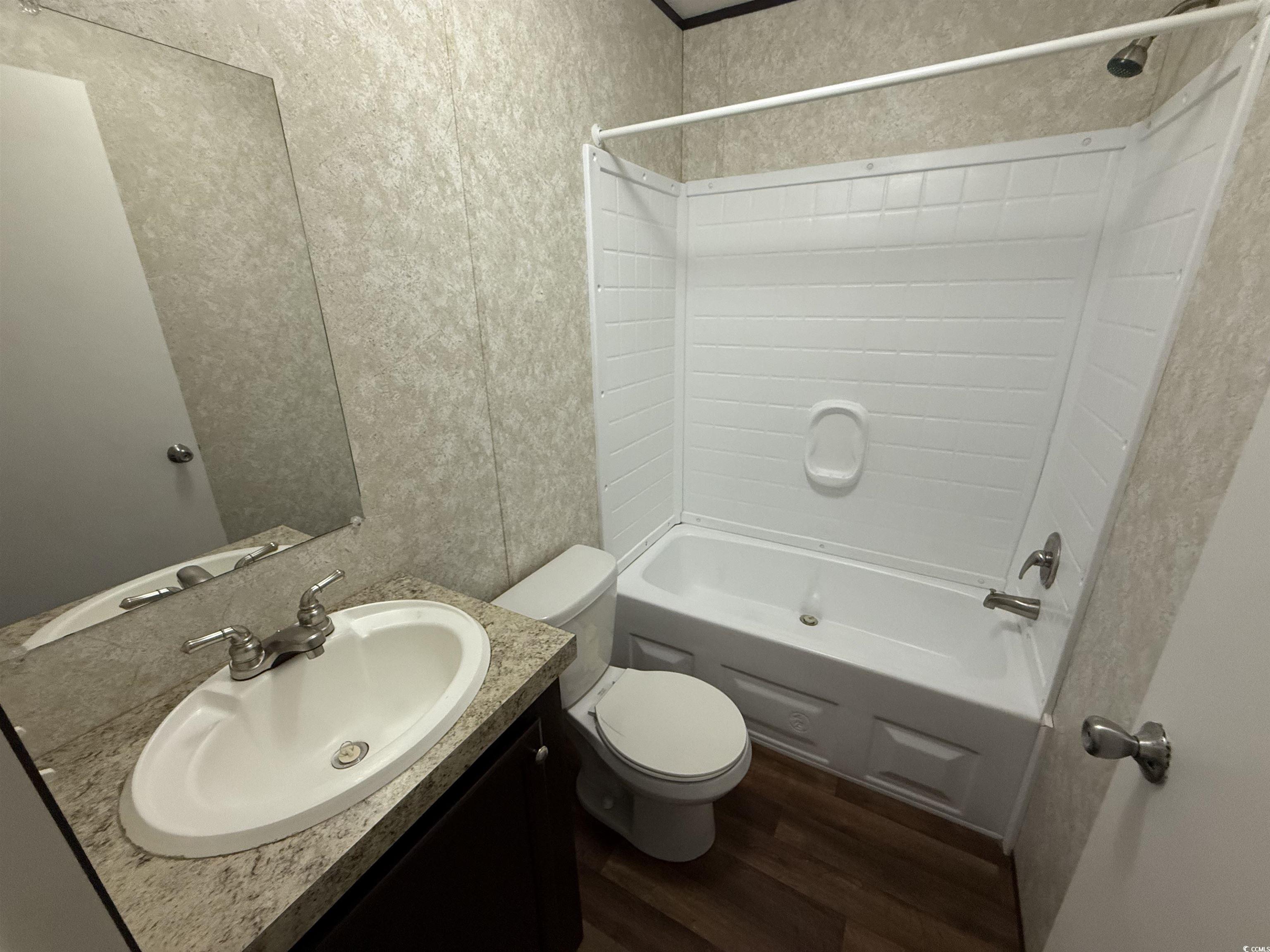 131 Shetland Woods Drive Myrtle Beach, SC 29577 - Photo 17 of 20 Full bath with washtub / shower combination, dark wood-style floors, vanity, and a textured wall