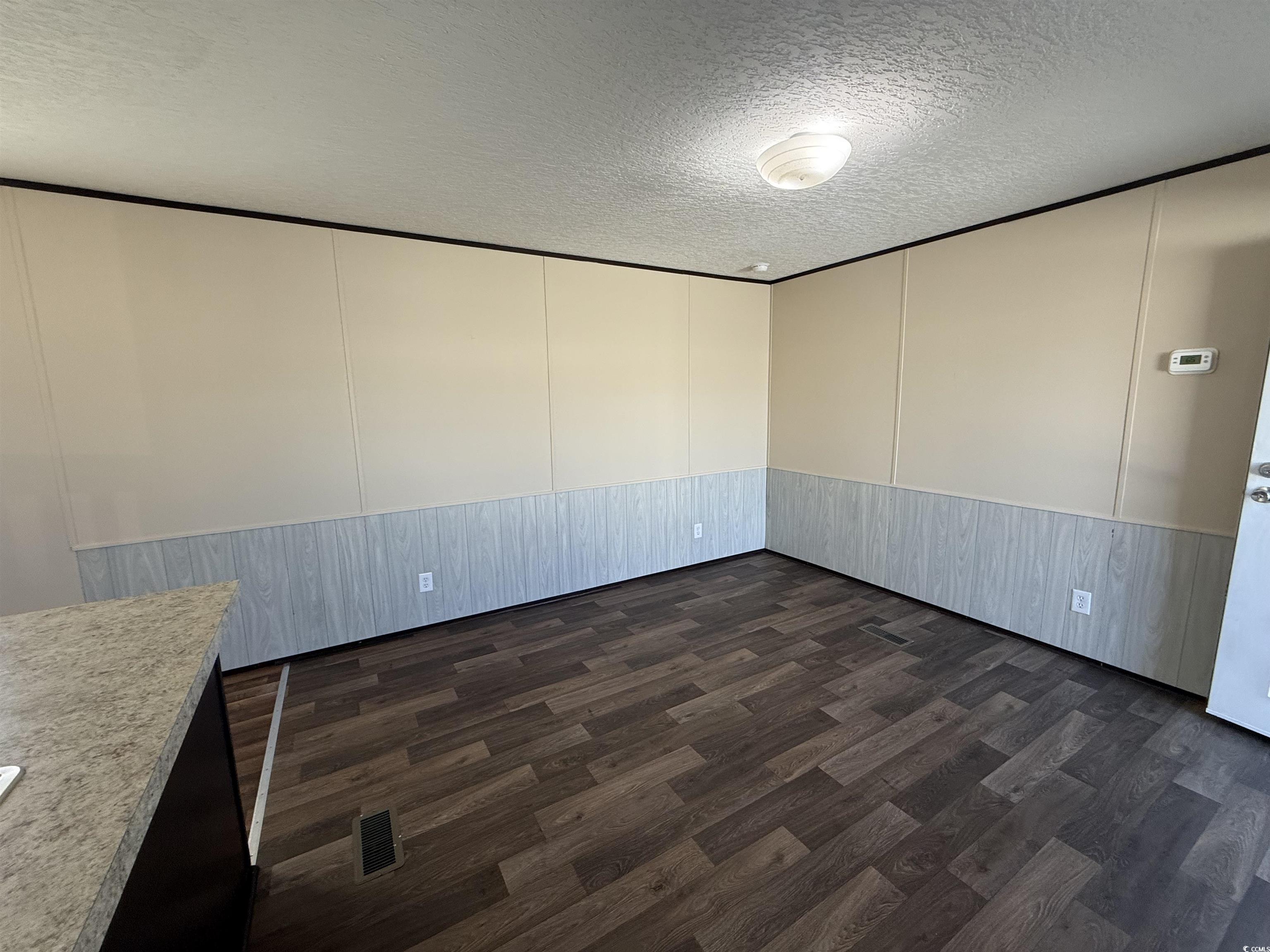 131 Shetland Woods Drive Myrtle Beach, SC 29577 - Photo 6 of 20 Unfurnished room with a textured ceiling, dark wood-style floors, and a decorative wall