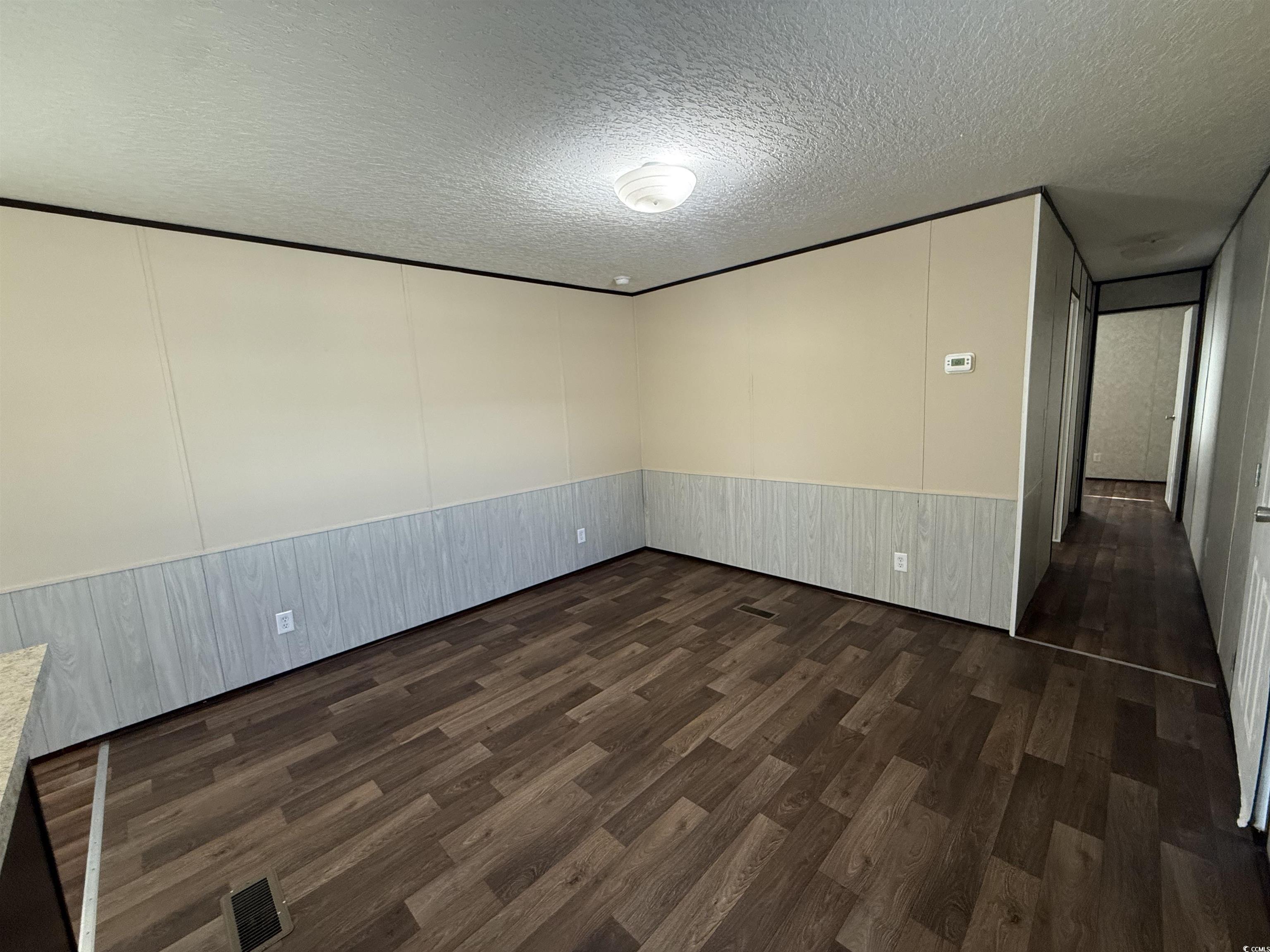 131 Shetland Woods Drive Myrtle Beach, SC 29577 - Photo 9 of 20 Empty room with dark wood-type flooring, a textured ceiling, and a wainscoted wall