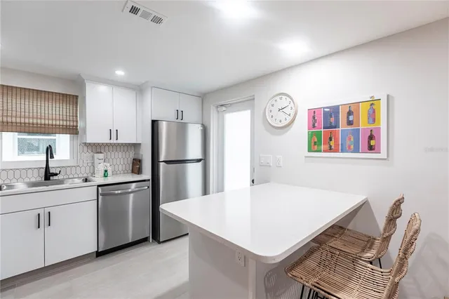 a kitchen with a sink a stove a refrigerator and white cabinets