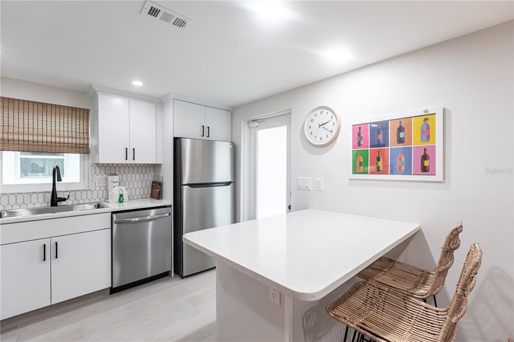 6154 Midnight Pass Road, Unit B18 Sarasota, FL 34242 - Photo 6 of 20 a kitchen with a sink a stove a refrigerator and white cabinets