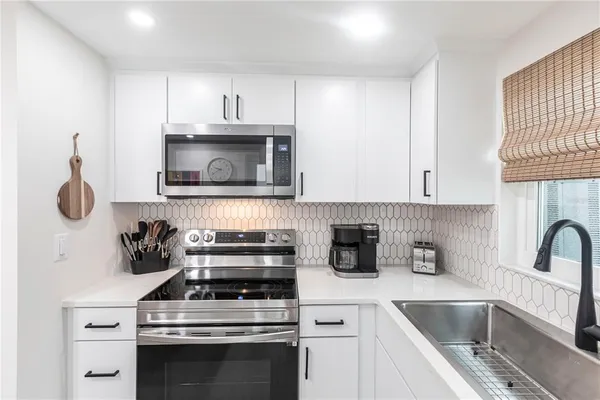 a kitchen with granite countertop a stove a sink and a microwave