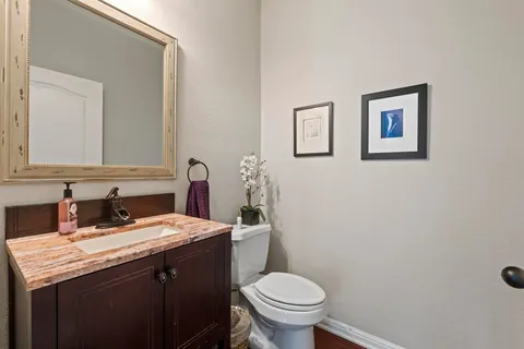 a bathroom with a granite countertop sink and a toilet