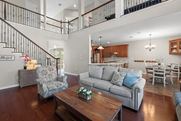 a living room with furniture kitchen view and a wooden floor