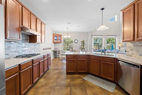 a large kitchen with stainless steel appliances granite countertop a stove a sink dishwasher and a refrigerator