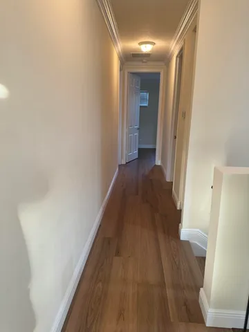 a view of a hallway with wooden floor and staircase